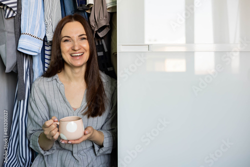 Portrait happy domestic woman posing wardrobe storage organization. Wooden furniture cabinet design photo