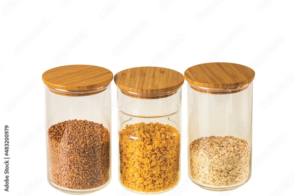 Close up view of three glass jars with cereals, buckwheat and pasta isolated on white background. Kitchen and healthy food concept. Close up view of three glass jars with cereals, buckwheat and pasta isolated on white background. Kitchen and healthy food concept.