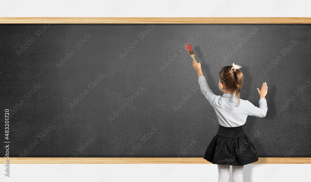 Student child writes with chalk on a blackboard solution of an example in mathematics. Student child writes with chalk on a blackboard solution of an example in mathematics.