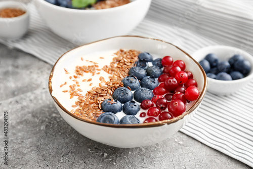 Bowl of sweet yogurt, flax seeds and berries on grunge background