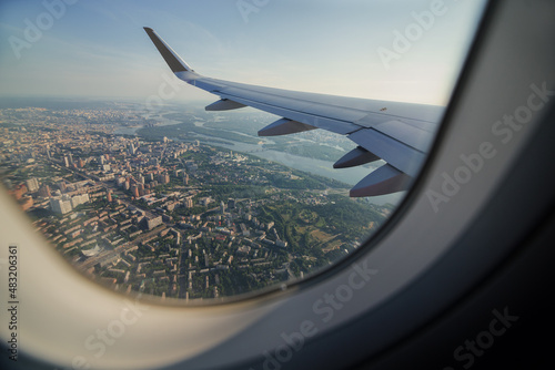 View from airplane window on the wing. Airplane going for landing. Plane Window as Descending Over Metropolitan Urban City Landscape.
