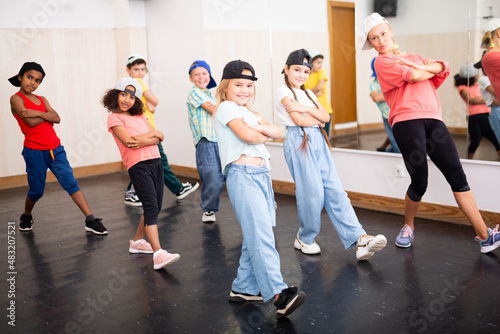 Cheerful preteen girls and boys hip hop dancers doing dance workout with female trainer during group class..