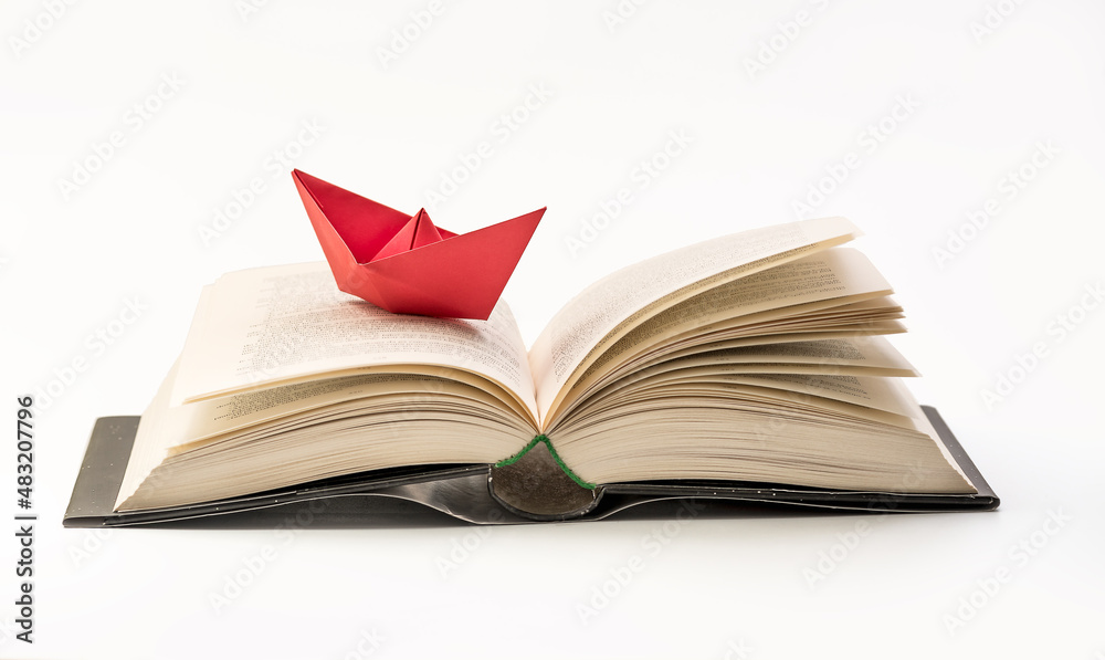  Origami red paper boat on a book. Close up Macro photography. Concept of traveling and 

research - knowledge