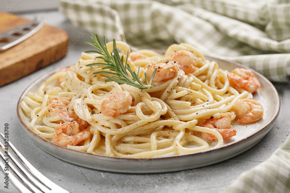 Flat plate with pasta spaghetti with heavy cream and roasted shrimps with garlic sauce and parmesan cheese on grey concrete surface