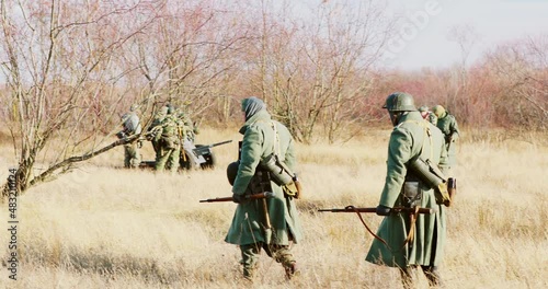 Re-enactors Dressed As German Infantry Soldiers In World War II Marching Walking Along Meadow In Cold Autumn Day. photo