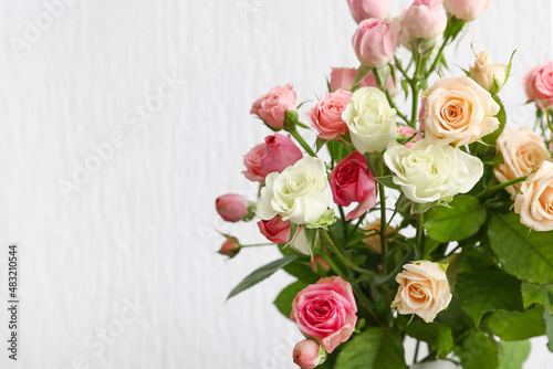 Vase with bouquet of beautiful roses on light background