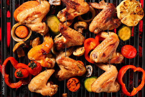 Tasty chicken wings skewers with vegetables on grill