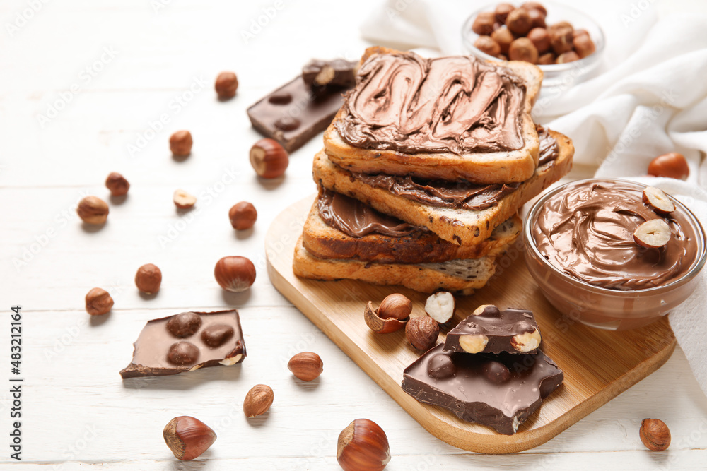 Board of bread with chocolate paste and hazelnuts on white wooden background Board of bread with chocolate paste and hazelnuts on white wooden background