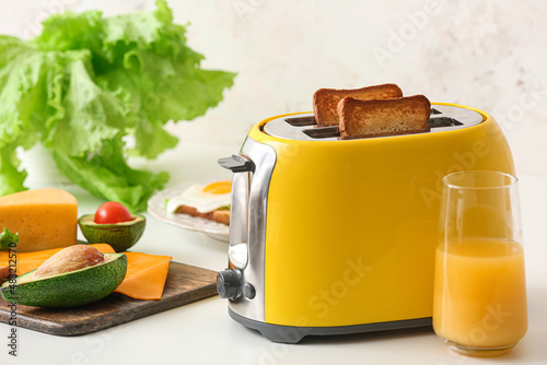Yellow toaster with healthy food and drink on table in kitchen
