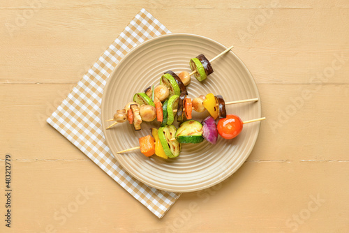 Plate with tasty vegetable skewers on wooden background