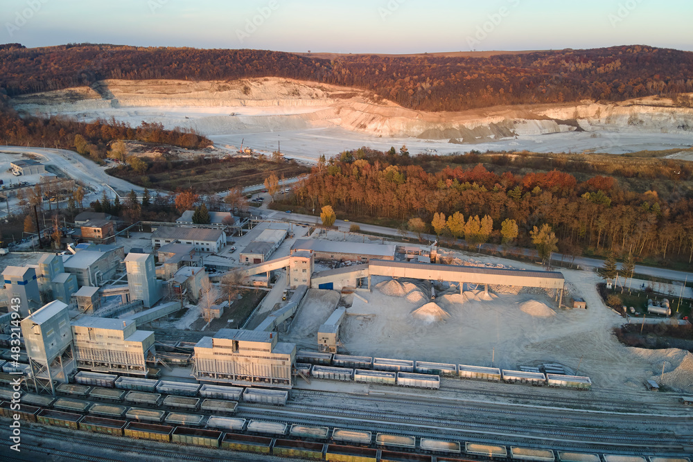 Fototapeta premium Aerial view of cargo train loaded with crushed stone materials at mining factory. Railway transportation of grinded limestone ore