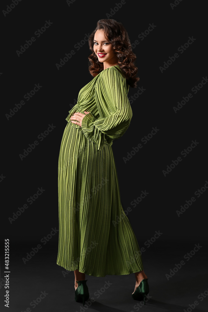 Fashionable woman in trendy dress posing on dark background