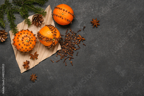 Handmade Christmas decoration made of tangerines with cloves and fir branch on dark background photo