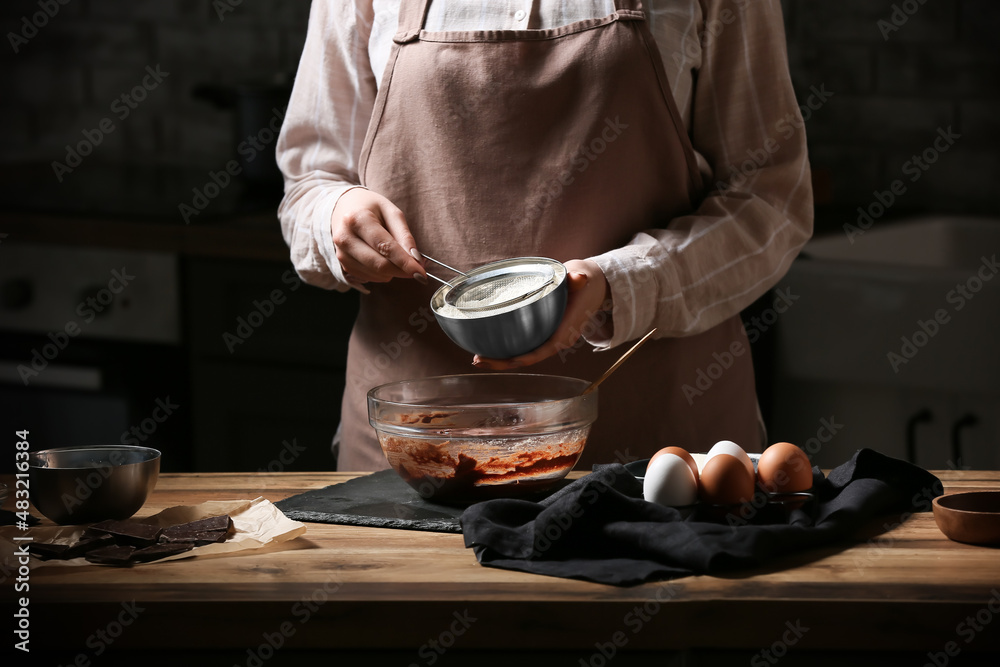 Woman adding flour for preparing chocolate brownie at kitchen table, closeup Woman adding flour for preparing chocolate brownie at kitchen table, closeup