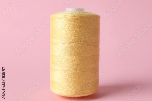 Yellow sewing thread spool on color background