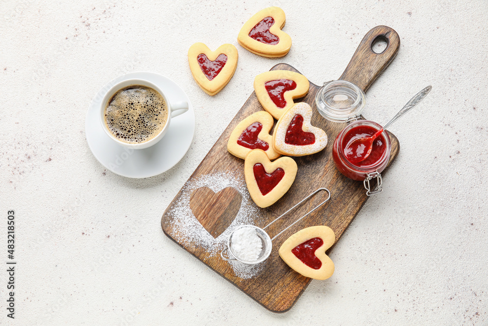 Board with tasty cookies and cup of coffee for Valentine's Day celebration on light background