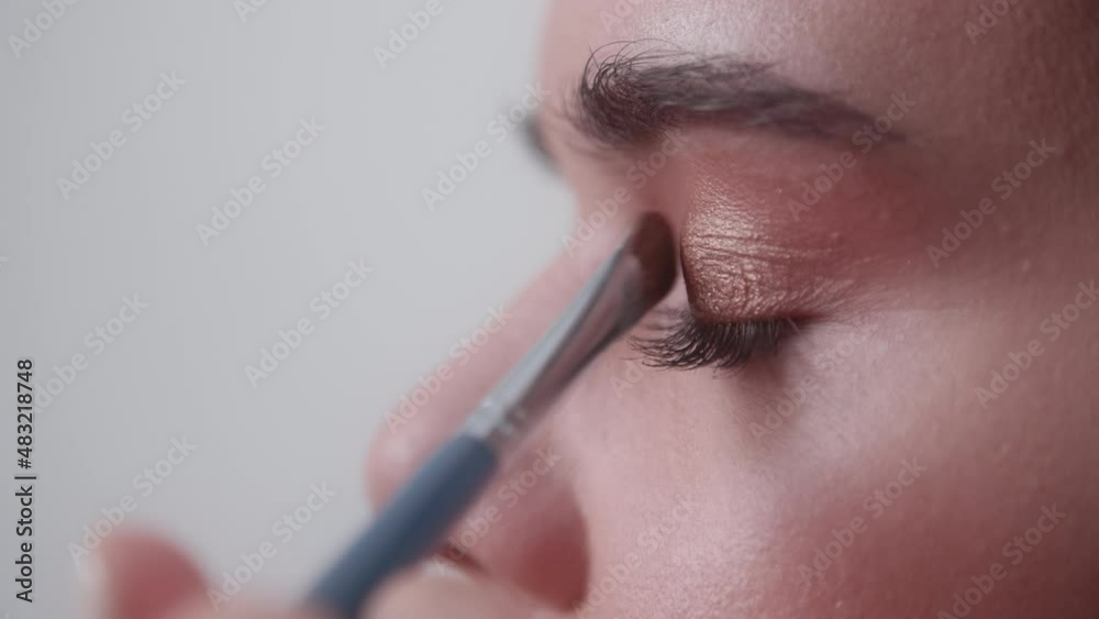 Close-up of young fashion model beautiful transformation. Portrait of applying pinky eyeshadow on the eye of a woman. High quality 4k footage