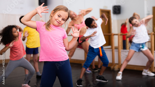 Fototapeta Naklejka Na Ścianę i Meble -  Portrait of little girl doing exercises during group class in dance center