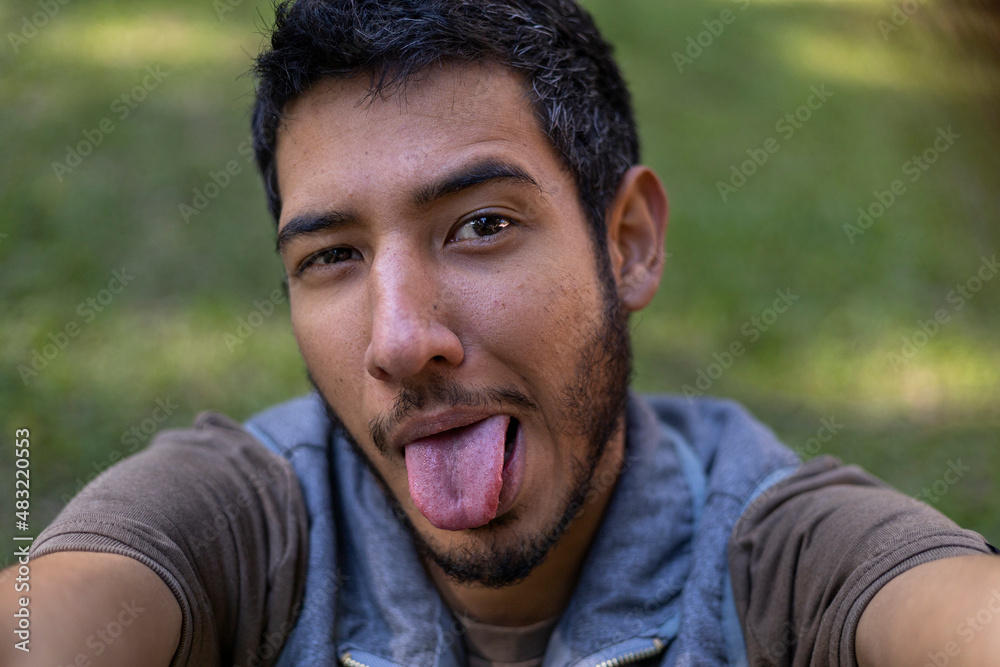 Self portrait of Latin American young adult (24) sticking out his tongue in amusing gesture. Technology concept and facial gestures. Self portrait of Latin American young adult (24) sticking out his tongue in amusing gesture. Technology concept and facial gestures.