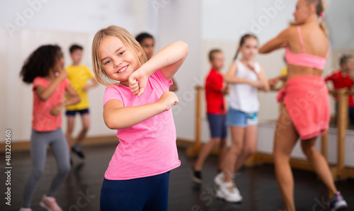 Fototapeta Naklejka Na Ścianę i Meble -  Portrait of emotional girl doing dance workout during group class in studio