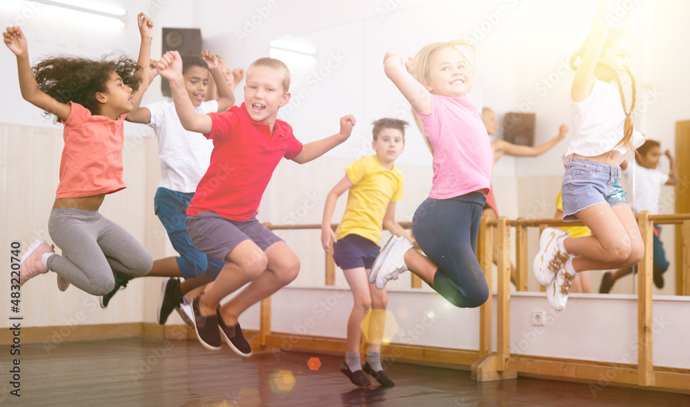 Happy kids of different nationalities and ages jumping during class in dance school