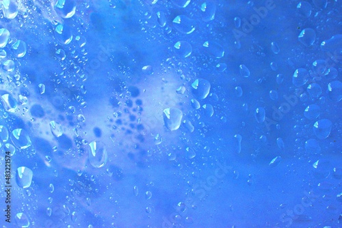 Abstract water droplets texture background on clear blue glass close-up