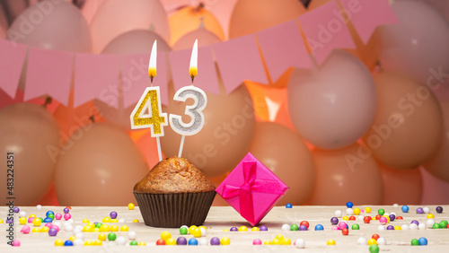 Decorations with balloons and a happy birthday candle with the number 43 for a woman. Happy birthday greetings in pink flowers for forty-three years old for an adult girl, copy space. Muffin  photo