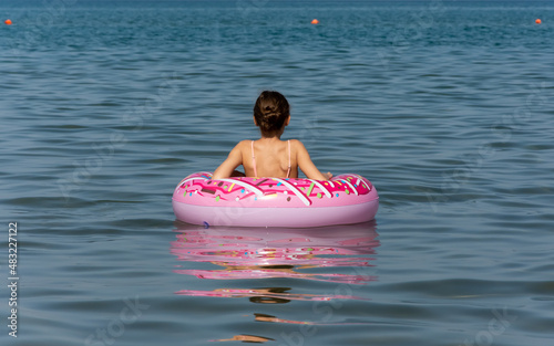 Girl sitting on inflatable ring at summer beach