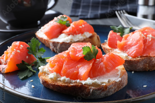 Tasty bruschettas with salmon, cream cheese and parsley on plate, closeup