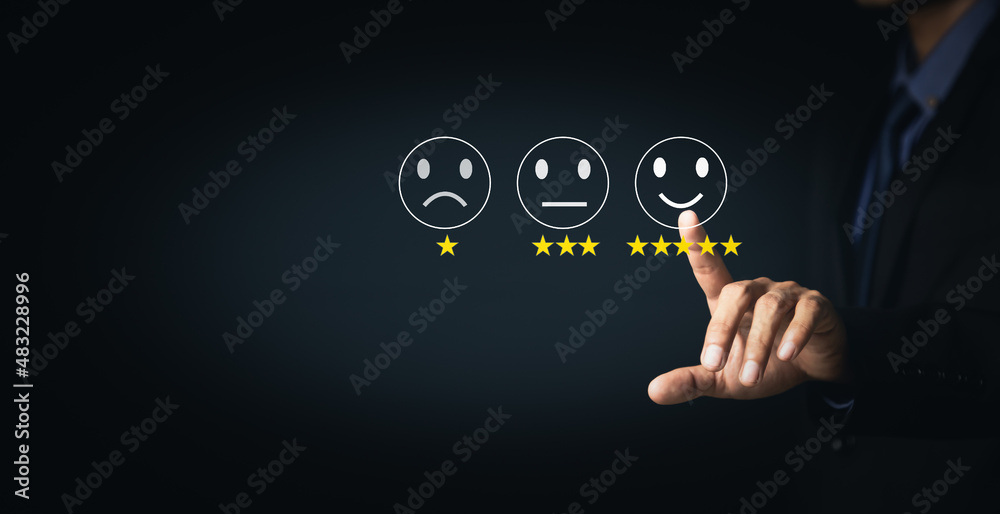 Fototapeta premium Customer Service and Satisfaction Concept Businessmen touch the virtual screen on happy smiley icons to achieve service satisfaction and feedback with excellent rated reviews.