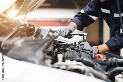 Mechanic works on the engine of the car in the garage. Repair service. Concept of car inspection service and car repair service.