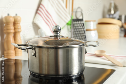 Shiny pot on electric stove in kitchen. Cooking utensil