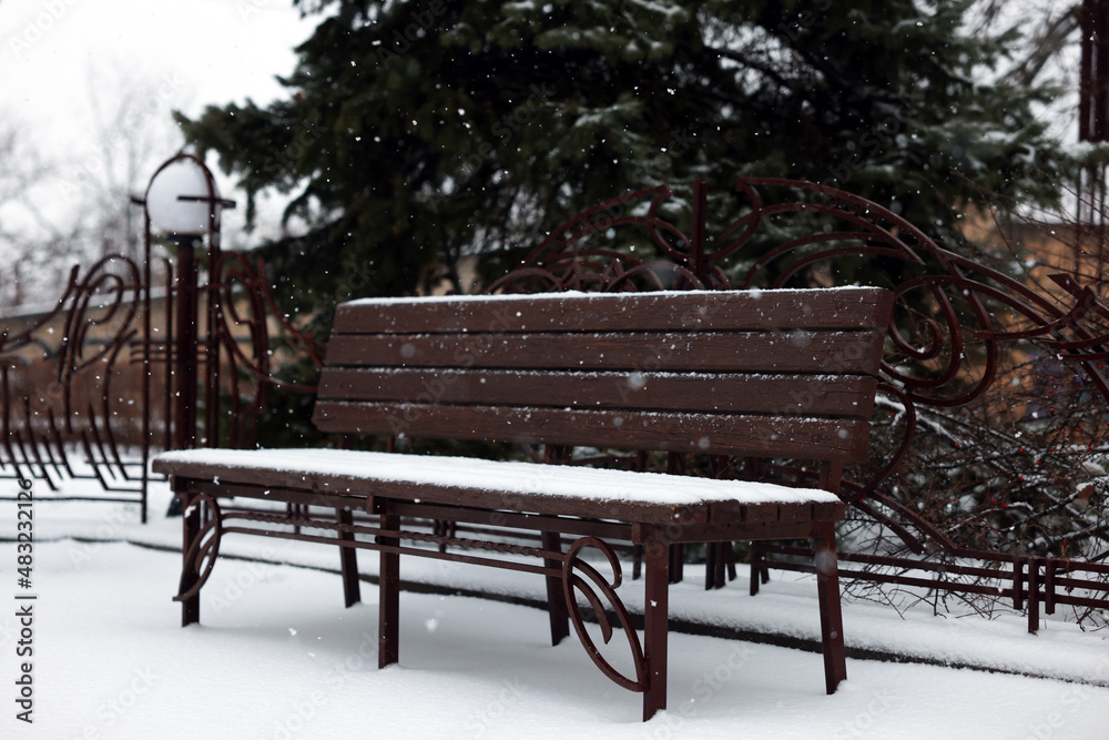Bench covered with snow in city park