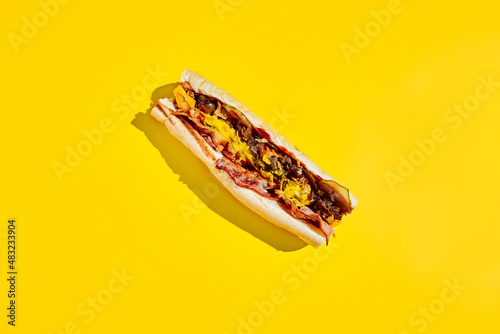 Beef cheesesteak in minimal style. American fast food in yellow background with shadow. Philly steak sandwich trendy concept. Junk food in colour background.