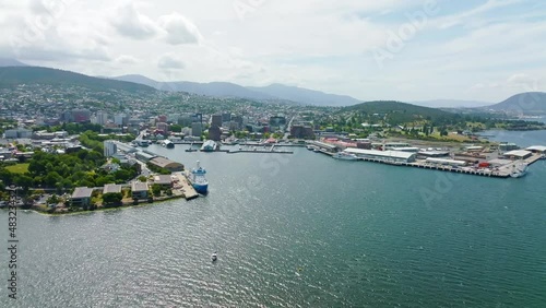 High angle aerial drone footage of Sullivans Cove, the harbour area of Hobart, capital of the island state of Tasmania, Australia. Mount Wellington in the background is covered in clouds.