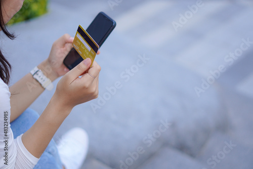 Young woman holding credit card and smartphone online shopping with blurred background