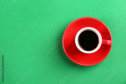 Cup of tasty coffee on green background, top view. Space for text
