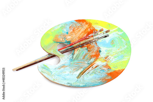 Artist's palette with mixed paints and brushes isolated on white