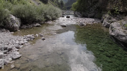 Drone video of ascending frontal plane advancing over the interior of the Cemi river on the Sh20 road between the mountains in Albania between Tamarë and Selcë, cloudy sky and turquoise river waters. photo