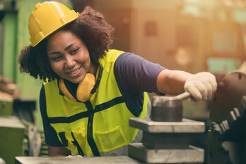 African American woman worker happy smiling working with metal machine in heavy industry factory
