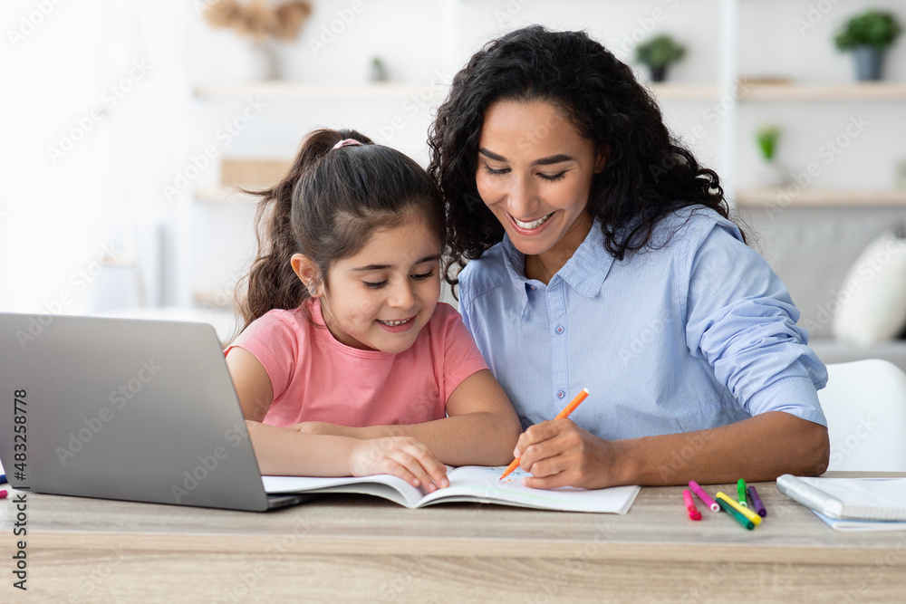 Homeschooling Concept. Caring Young Mom Helping With Homework To Her Little Daughter Homeschooling Concept. Caring Young Mom Helping With Homework To Her Little Daughter