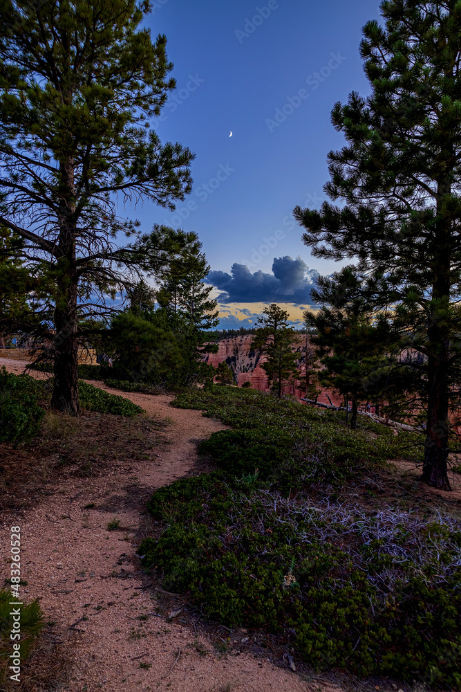 Darkness envelopes the Hoodoos and orange granite of Bryce Canyon National Park. The stars appear, silhouettes of tree lined hills bring a hush over the Utah wilderness
