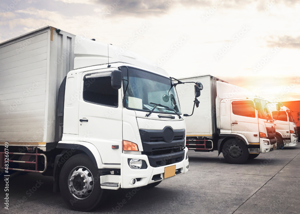 Cargo Trucks Parked Lot at The Sunset Sky. Shipping Cargo Trucks. Delivery Lorry. Industry Freight Truck Logistics Distribution Cargo Transport Concept.