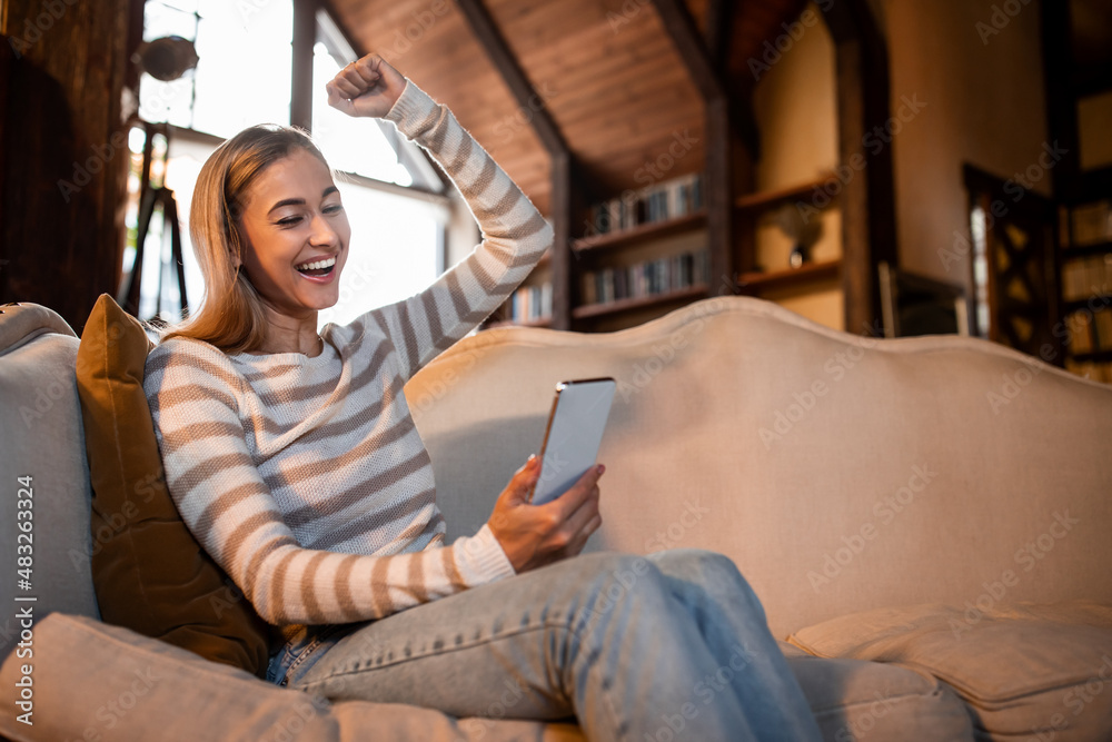 Excited woman using phone shaking clenched fist Excited woman using phone shaking clenched fist