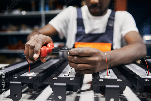 Man holding wires with tongs, working manually