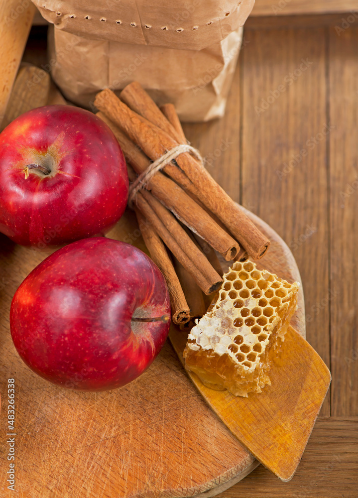honey spoon, jar of honey, apples and cinnamon on a wooden background in a rustic style