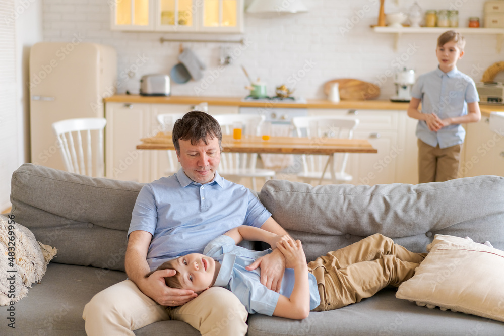 © Екатерина Переславце - Happy caucasian father and little sons are having fun together, laughing dad hugs, tickling cute baby, sitting together on sofa at home in kitchen, enjoying the weekend, having fun together close-up © Екатерина Переславце - Happy caucasian father and little sons are having fun together, laughing dad hugs, tickling cute baby, sitting together on sofa at home in kitchen, enjoying the weekend, having fun together close-up