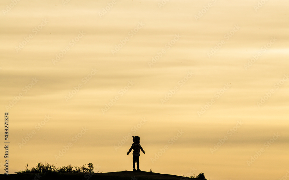 Silhouette Of Young Girl With Open arms Facing The Sunset