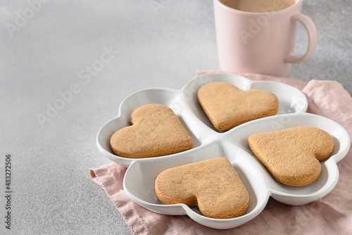 Heart shaped cookies on white combination plate for Valentine's Day on gray background. View from above. Space for your greetings.