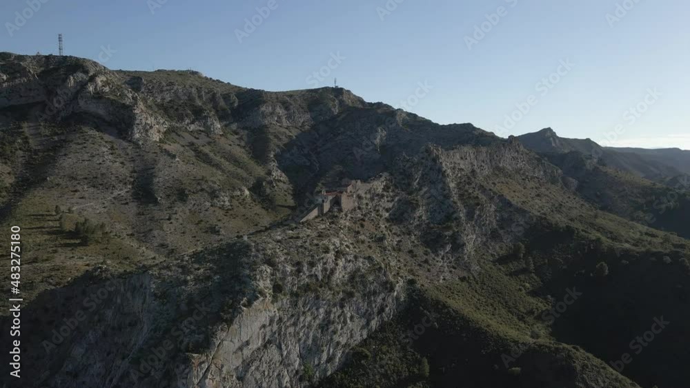 Fly over dry rugged rocky landscape to escarpment hermitage chapel Fly over dry rugged rocky landscape to escarpment hermitage chapel